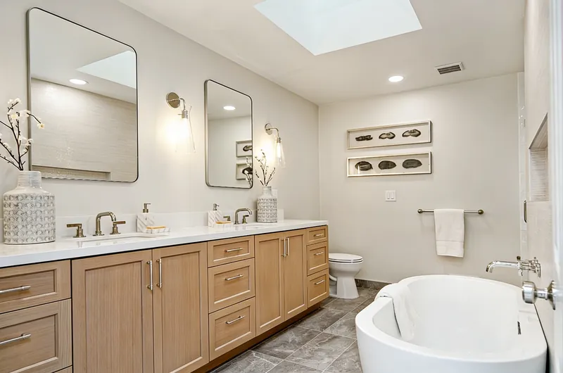 Remodeled bathroom with double vanity, freestanding tub and skylight