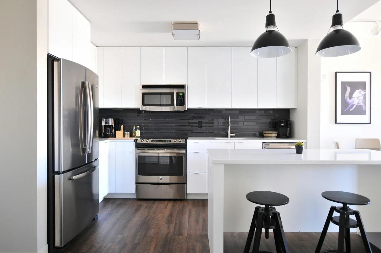 Bright kitchen with white cabinetry, a range and black pendant lights